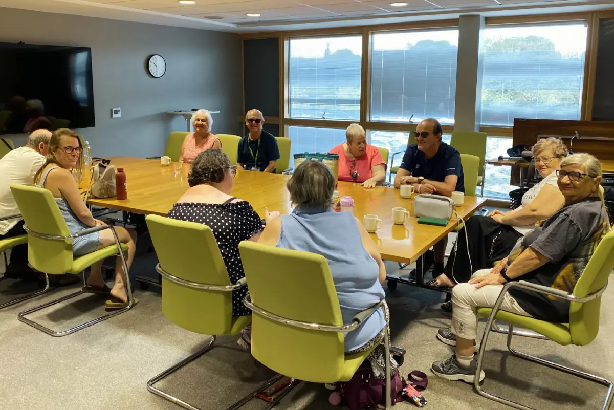 Boardroom at Frome Medical Practice with a large rectangular table in the centre of the room and ten people seated around it.